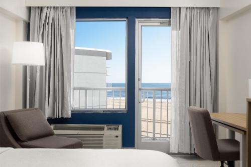a hotel room with a bed and a desk and chairs at Spark by Hilton Virginia Beach Oceanfront in Virginia Beach