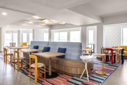 a waiting room with tables and chairs and windows at Home2 Suites by Hilton Outer Banks Kill Devil Hills in Kill Devil Hills