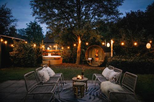 a patio with chairs and a table with lights at Bohemian Wellness met hottub & sauna in Ewijk