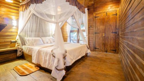 a bedroom with a canopy bed and a window at Cozora Nook - Sigiriya in Sigiriya