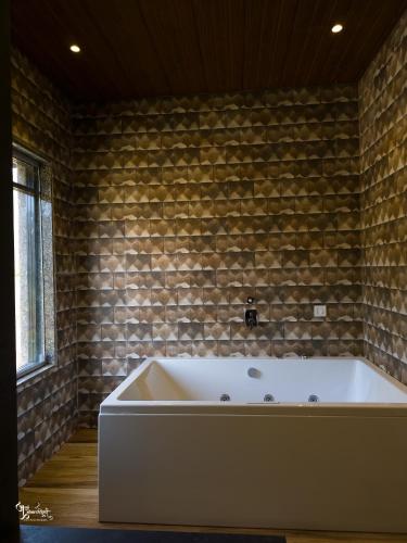 a bath tub in a room with a brick wall at Miransh Heavenly in Dapoli