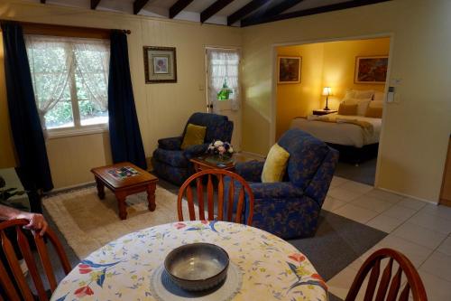 a living room with a bed and a table and chairs at Curtis Cottage in Mount Tamborine