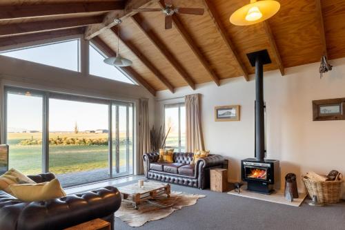 a living room with leather furniture and a wood stove at Omahau Down in Lake Pukaki