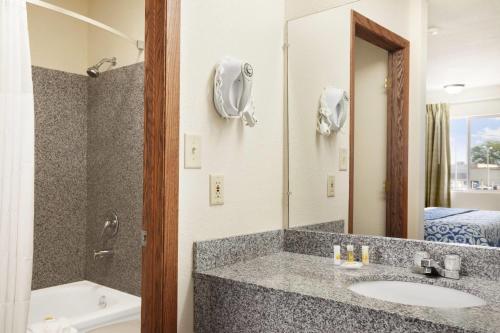a bathroom with a sink and a mirror at Days Inn by Wyndham Champaign/Urbana in Champaign