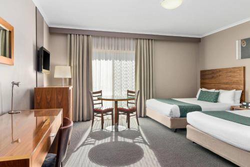 a hotel room with two beds and a table at Quality Hotel Dickson in Canberra