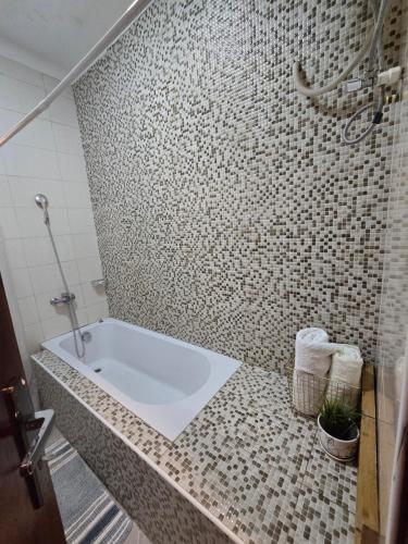 a bathroom with a tub and a tiled wall at Gamaleo Apartment Namulanda in Namulanda
