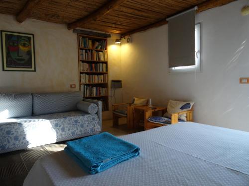 a bedroom with a bed and a couch and a tv at La Scala Guesthouse in Berchiddeddu