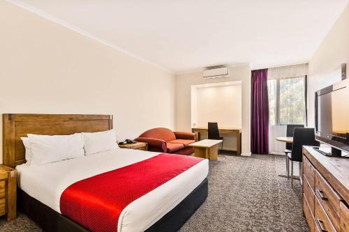 a hotel room with a bed and a flat screen tv at Quality Hotel Manor in Mitcham