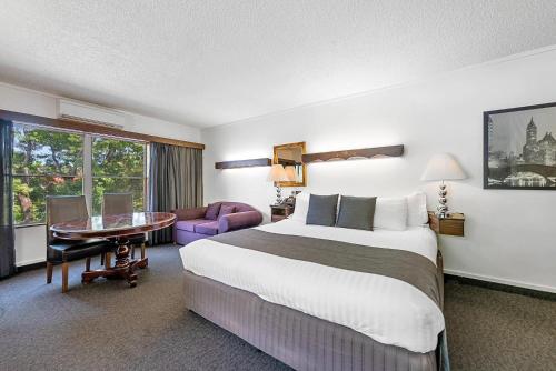 a hotel room with a large bed and a desk at Quality Hotel Colonial Launceston in Launceston