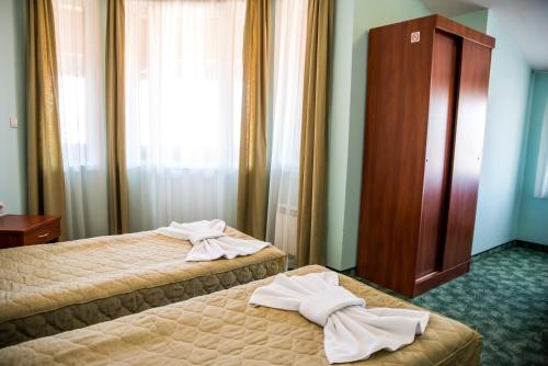 two beds in a hotel room with towels on them at Bariakov Family Hotel in Bansko