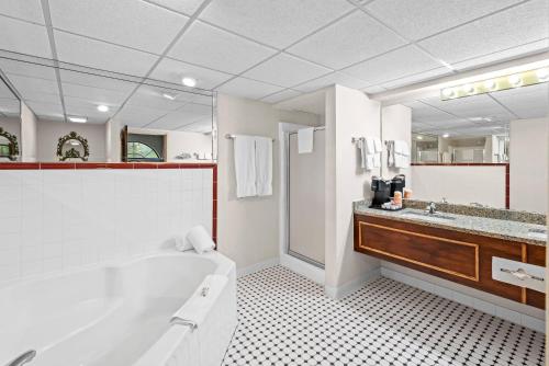 a white bathroom with a tub and a sink at Clarion Inn Branson in Branson