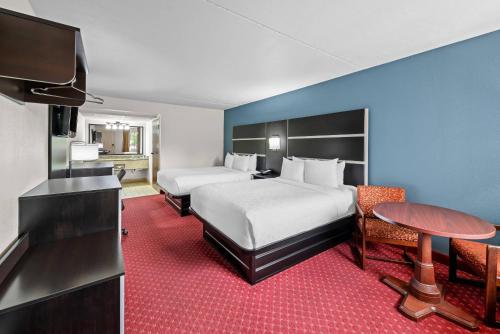 a hotel room with two beds and a flat screen tv at Clarion Inn Branson in Branson