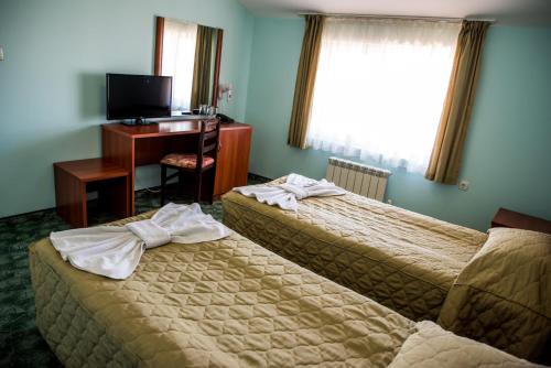 a hotel room with two beds and a desk and a television at Bariakov Family Hotel in Bansko
