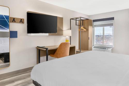 a hotel room with a bed and a desk and a tv at Comfort Inn & Suites Springfield in Springfield