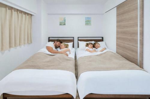 a man and two children laying on two beds at 801Room,Sky Tower 12 minutes walk Sensoji Temple 15 minutes walk New Apartment 50 m2 direct access to Haneda Airport in Tokyo