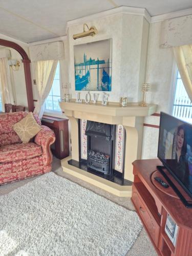 a living room with a fireplace and a tv at Caravan 6 berth in Ingoldmells