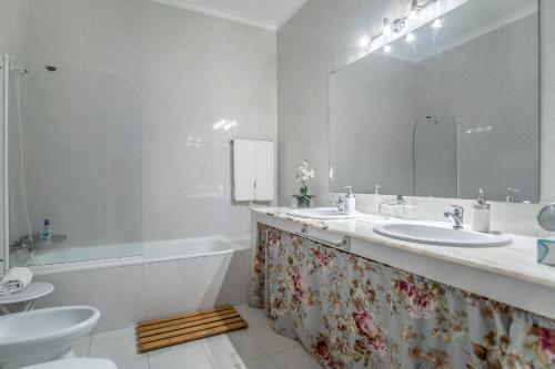 a bathroom with two sinks and a tub and a mirror at Casa Vitoriana in Ponta Delgada