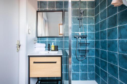 a bathroom with a sink and a shower with blue tiles at Le P'tit Bretzel in Turckheim