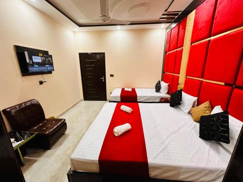 a hotel room with two beds and a chair at New Like Home Hotel in Lahore
