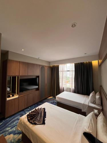 a hotel room with two beds and a television at Brisdale International Kuala Lumpur in Kuala Lumpur