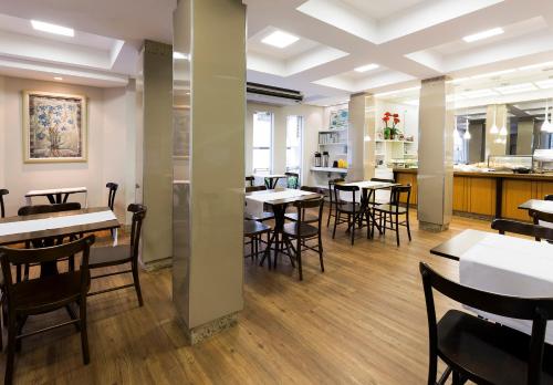 a restaurant with tables and chairs and a kitchen at Tropikalya Prime Hotel in Balneário Camboriú