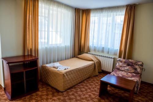a bedroom with a bed and a chair and a window at Bariakov Family Hotel in Bansko