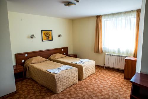 a hotel room with two beds and a window at Bariakov Family Hotel in Bansko