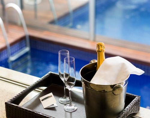 a bottle of champagne in a bucket next to two glasses at Tropikalya Gold Hotel in Balneário Camboriú
