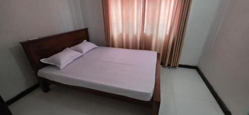 a bedroom with a bed with white sheets and a window at Silver Spring Villa in Siyambalape