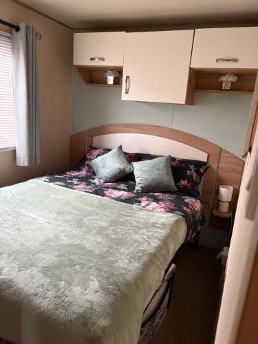 a small bedroom with a bed with flowers on it at Buckley's Retreat - 3 Bedroom Family Caravan overlooking fishing lakes at Golden Palm Resort in Chapel Saint Leonards