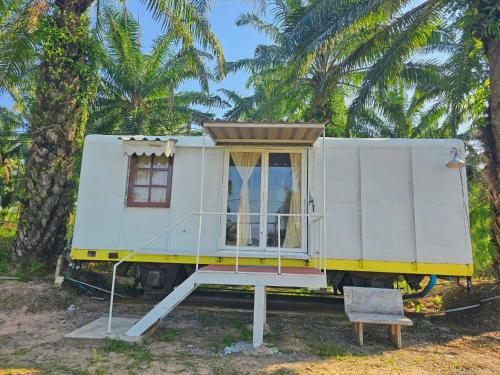 a tiny house on display in front of palm trees at ภูผาหน้าเล PhuPha-NaLay Cafe'n Camping in Ban Muang Thaeo