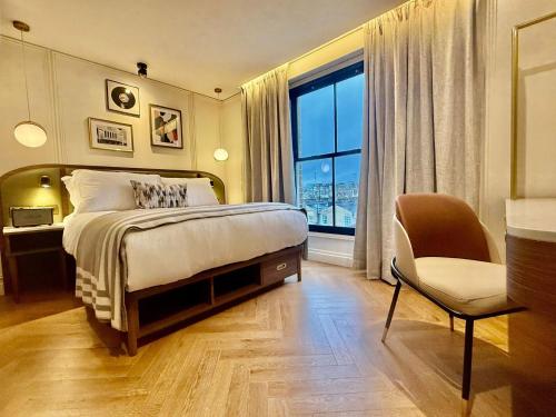 a bedroom with a bed and a chair and a window at The Barkston in London