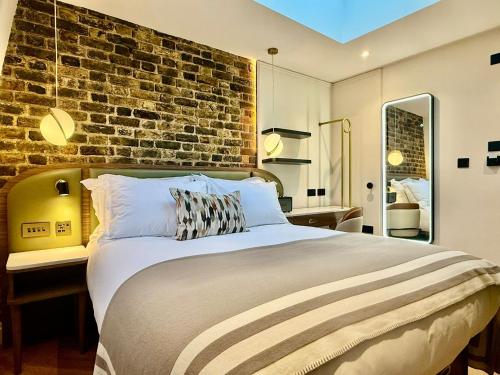 a bedroom with a large bed with a brick wall at The Barkston in London