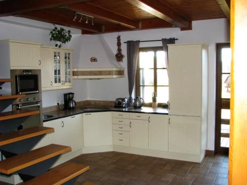 La cuisine est équipée de placards blancs et d'un four avec plaques de cuisson. dans l'établissement Pension Polubný 922, à Kořenov