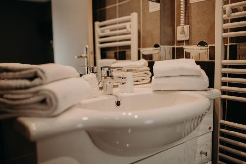 a bathroom with a white sink and towels at Logis - Hotel Restaurant du Parc in Cransac