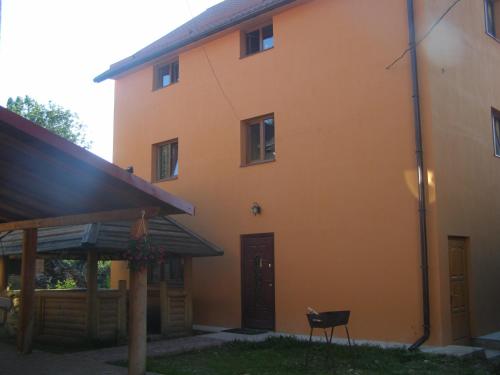 an orange house with a black door and a chair in front at Guest House Mandrivnyi Rooms&Apartments in Yasinya