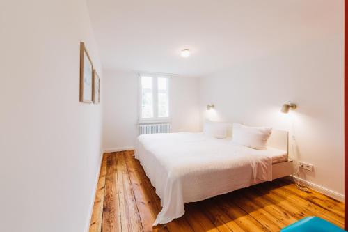 a bedroom with a bed with white sheets and wood floors at Kapitänshaus Wieck in Wieck