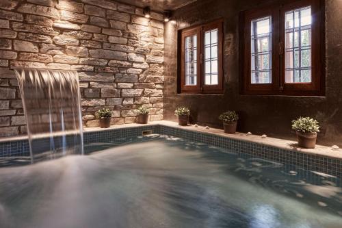 una piscina en una habitación con una pared de piedra en Hotel Dryades and Spa en Agios Lavredios