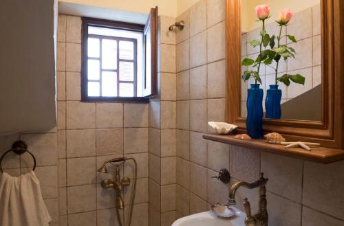 a bathroom with a sink and a shower with a window at Sappho House in Skala Eresou