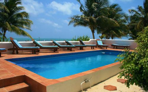 a swimming pool with lounge chairs and the ocean at Seaside Villas in Caye Caulker
