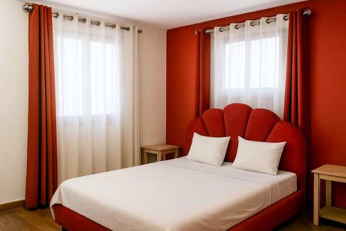 a bed with a red headboard and two windows at Akany Fitahiantsoa in Ivato