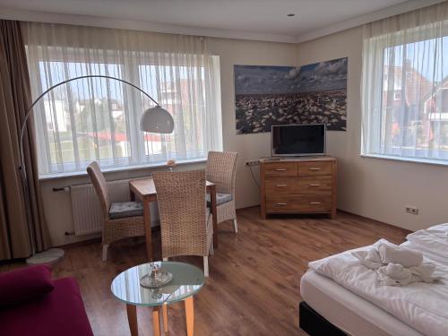 a living room with a table and a bed and a room at Pension Appartementhaus Hus Möhlenbarg in Cuxhaven