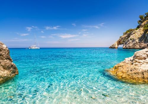 a boat in the ocean between two rocks at La Grotta Sardegna 5 Bedrooms each with a Private Ensuite Bathroom featuring a Hydromassage Shower Air Conditioning in Urzulei
