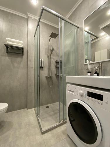 a washing machine in a bathroom with a shower at Contento Apartments in Almaty