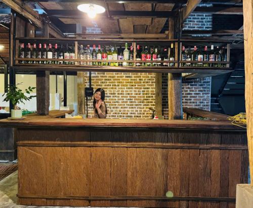 a woman is standing behind a bar with alcohol at Nabum Retreat in Làng Giang