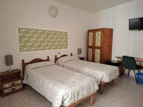 ein Schlafzimmer mit zwei Betten, einem Schreibtisch und einem Fernseher in der Unterkunft Hotel 4 Mori in Cagliari