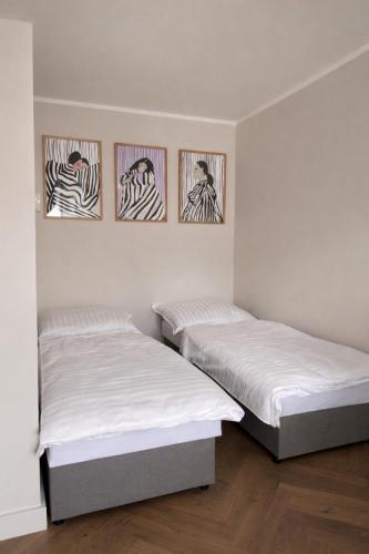 two beds in a room with three pictures on the wall at Studio Odrodzenia 5 Centrum Lubina in Lubin