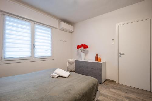 a bedroom with a bed and a vase of red flowers at Casa con parcheggio interno gratis e tram Venezia in Favaro Veneto