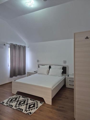 a bedroom with a white bed and a black and white rug at La Miruna in Comăneşti