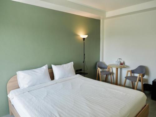 a bedroom with a white bed and a table and chairs at W Smart Stay TRANG in Trang